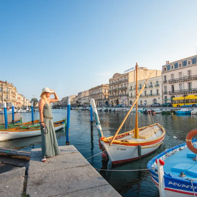 Junge Frau am Kai von Sète mit Blick auf die Kanäle und traditionelle Boote.Frau, allein, Boot, Landschaft, Kleid, Himmel, Wasser